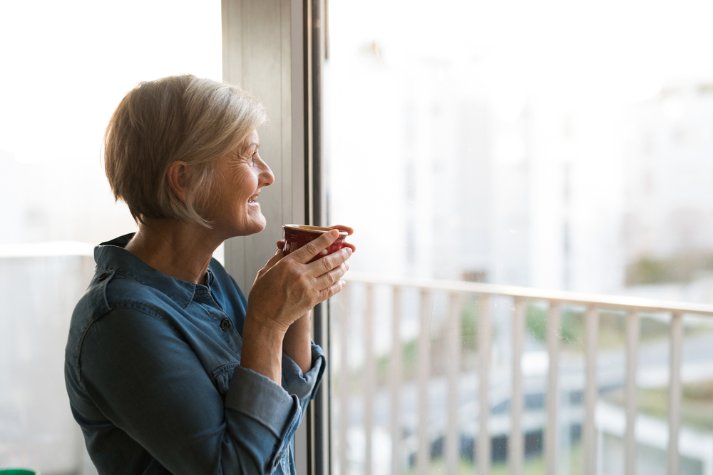 A senior looking out her apartment window.